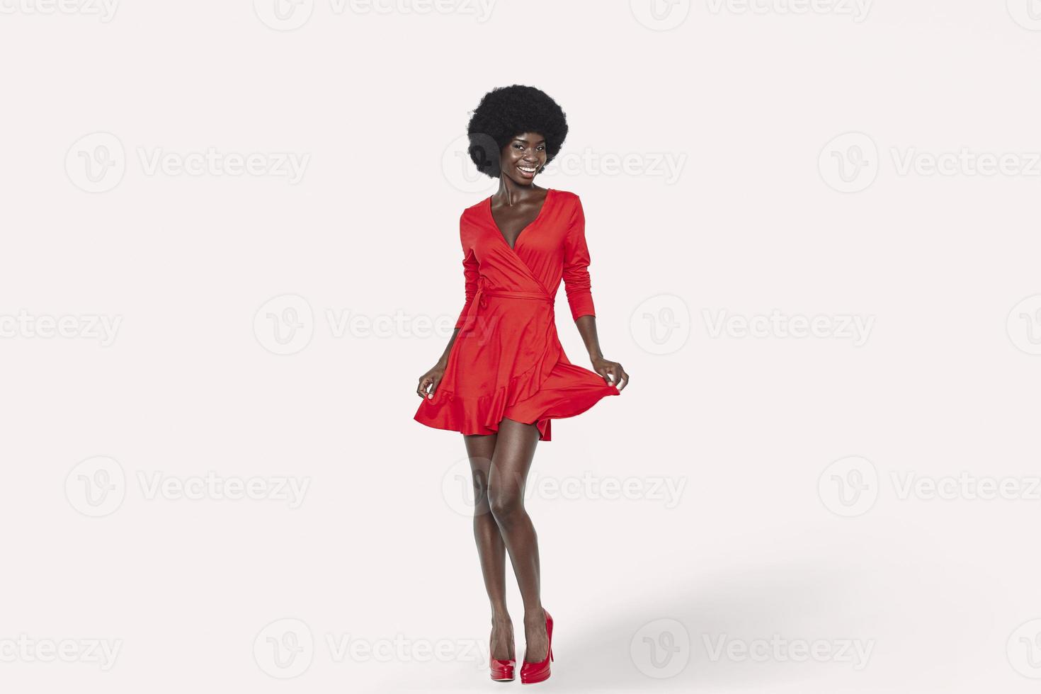 Full length of beautiful young African woman in red dress dancing against background photo