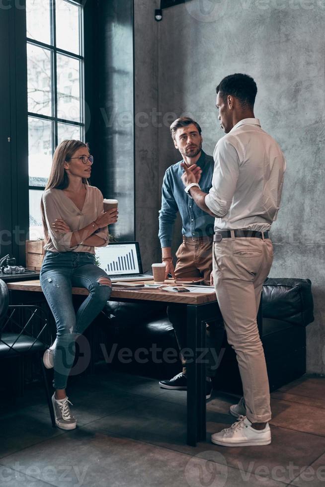 Group of young people in smart casual wear discussing business while working in the office photo