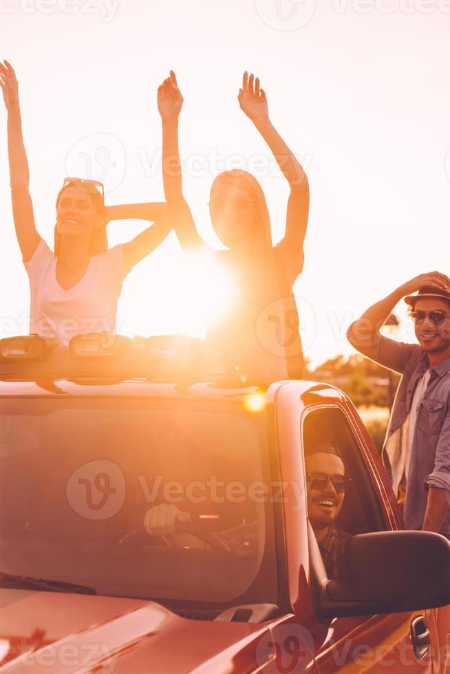 Road trip. Group of young cheerful people enjoying their road trip while sitting in pick-up truck together photo