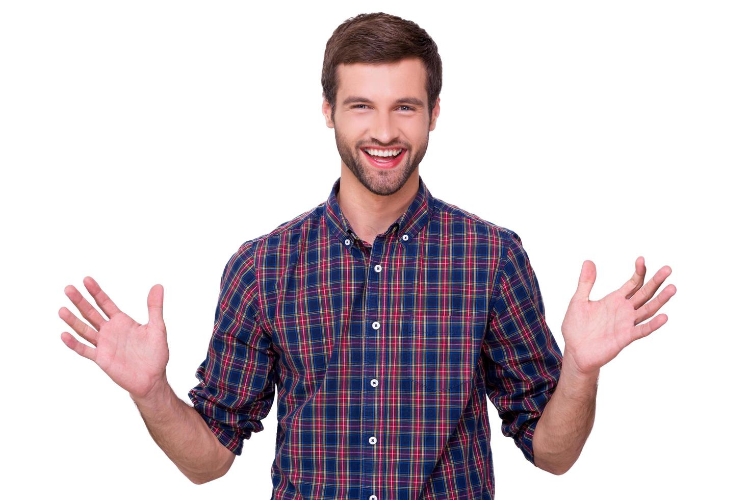 feliz guapo. joven feliz en camisa casual gesticulando y sonriendo mientras está de pie aislado en blanco foto