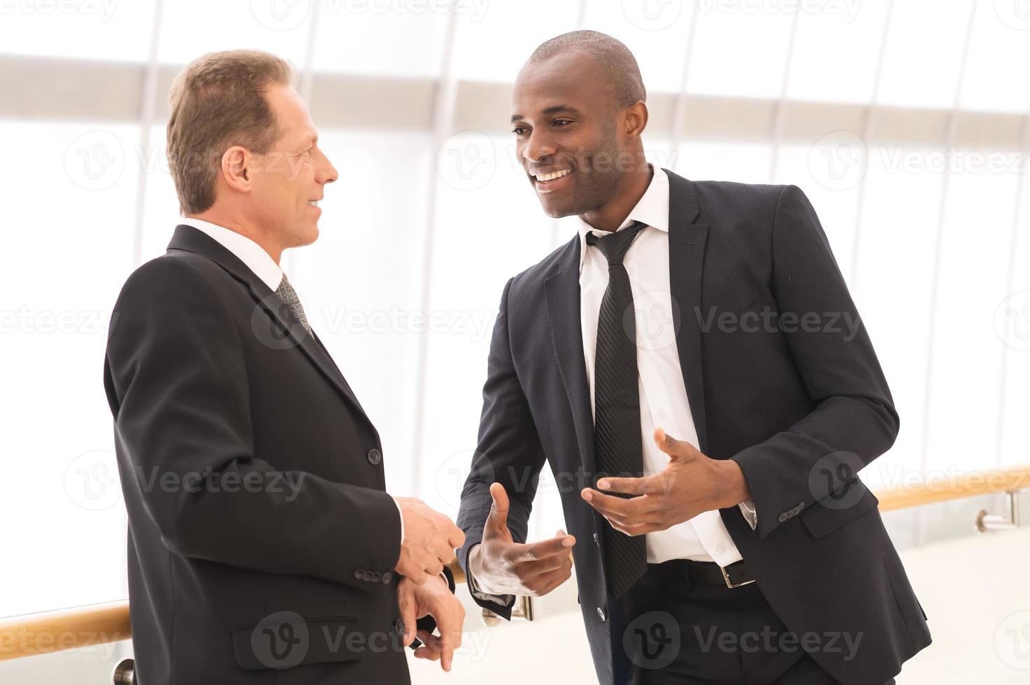 comunicacion de negocios. dos hombres de negocios alegres hablando entre ellos y gesticulando foto