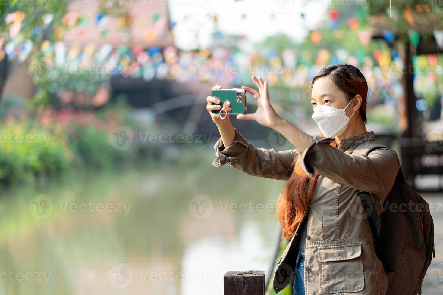 joven viajera asiática con máscara y mochila tomando fotos por móvil en ayothaya tailandia, concepto de relajación de vacaciones de viaje