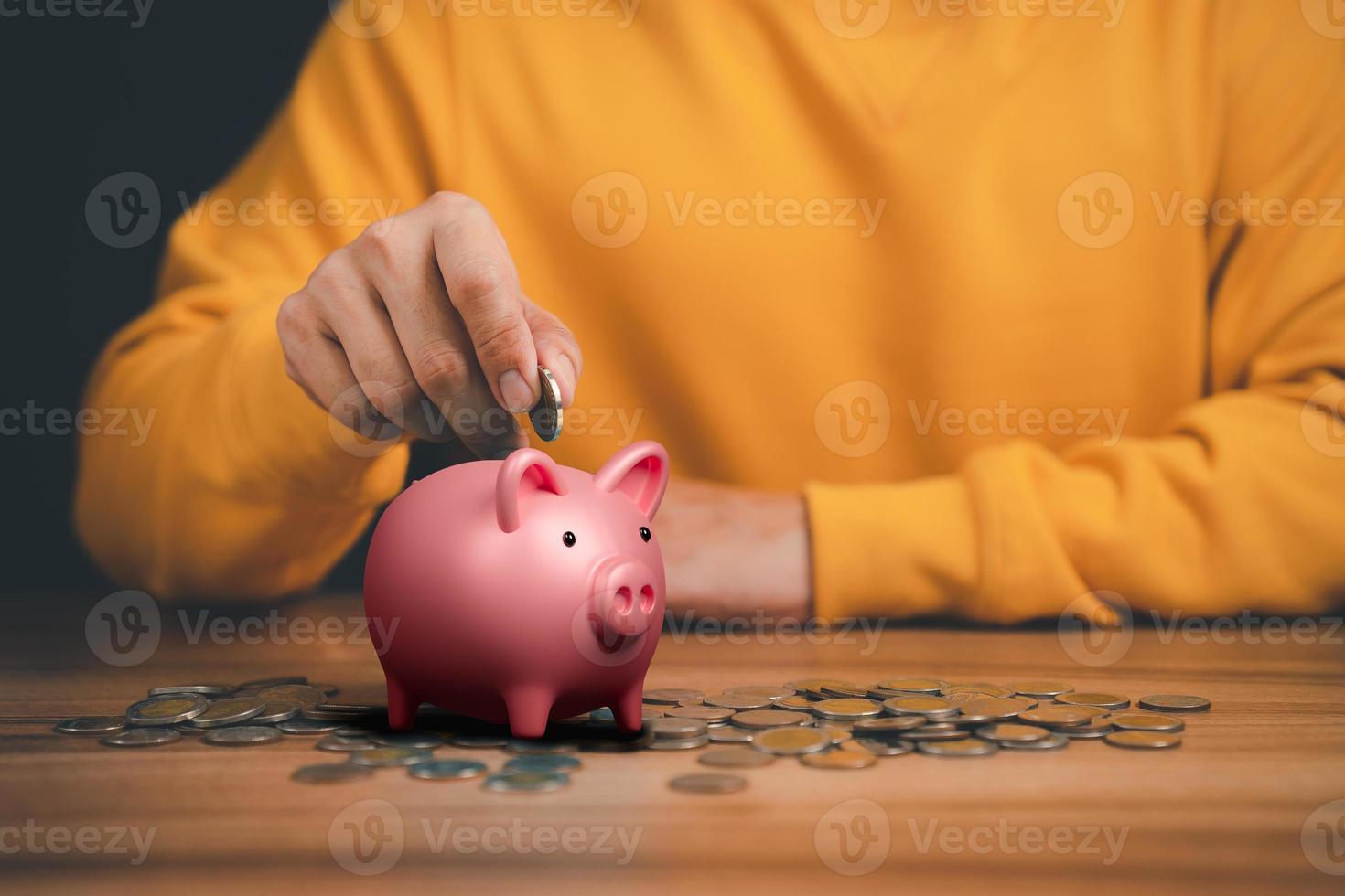 Man putting coin into piggy bank for saving money concept, business finance and investment. photo