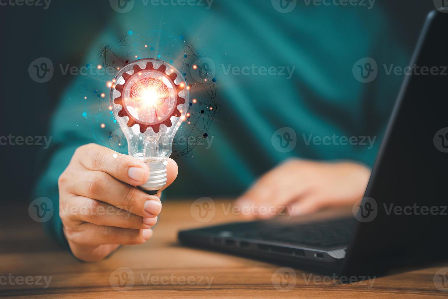 Man holding a light bulb while working on the computer to think and create new ideas with technological innovations and creativity Ideas inspired by online technology, innovations. photo