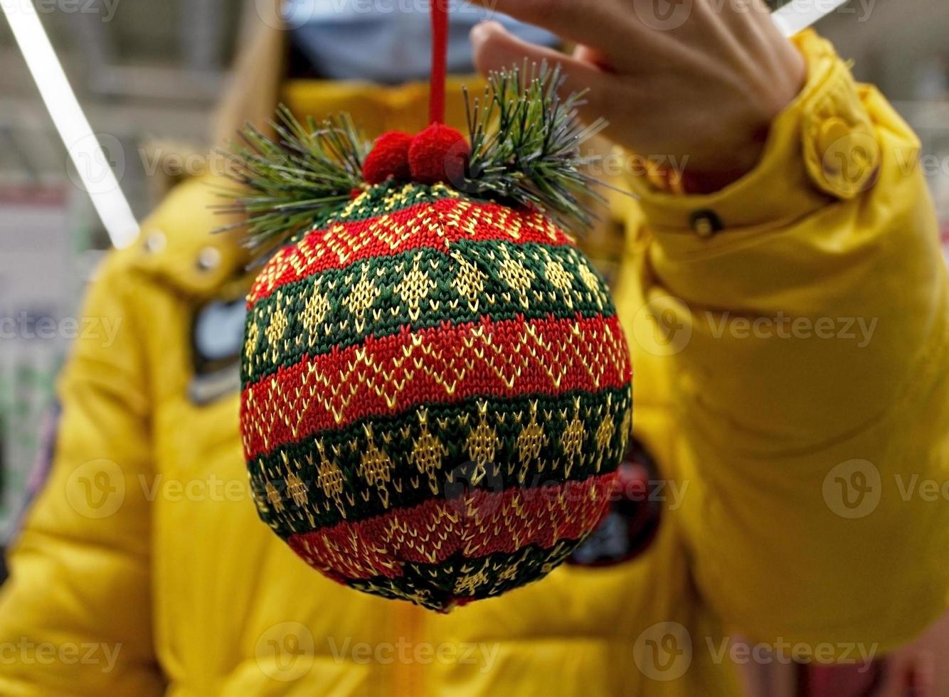 Red-green knitted Christmas ball in hand close-up. Christmas and New Year gift, background photo