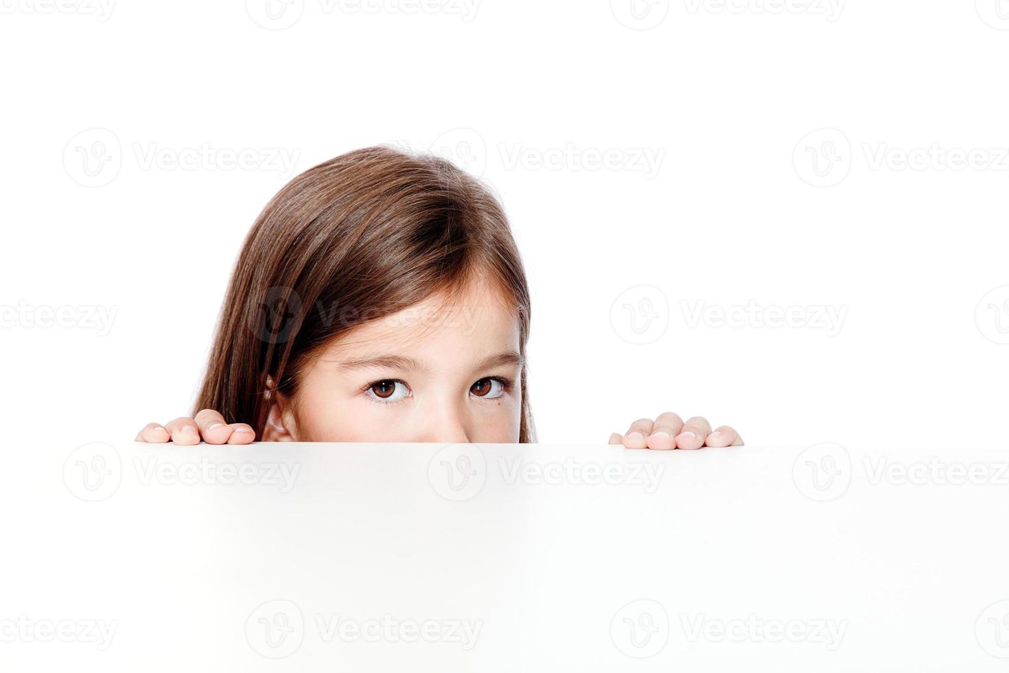 linda niña pequeña mirando hacia arriba en el escritorio de la escuela. foto