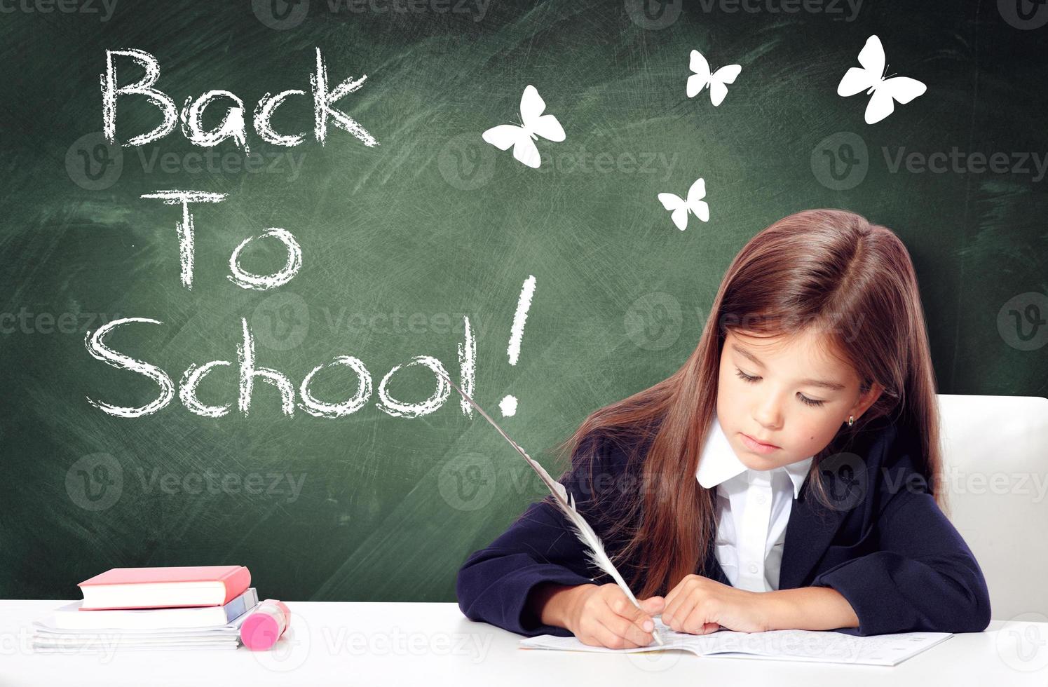 Happy and cute teen school girl writes in a book or notebook photo