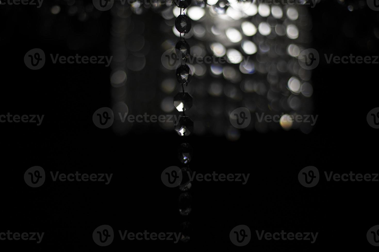 Crystal chandelier on black background. Interior details. Light in room. Light source. Glass sticks. photo