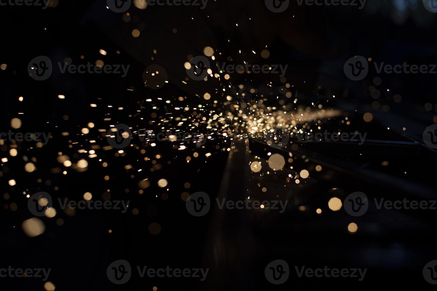 Sparks in dark. Stream of lights on black background. Metal crushing. High temperature. photo