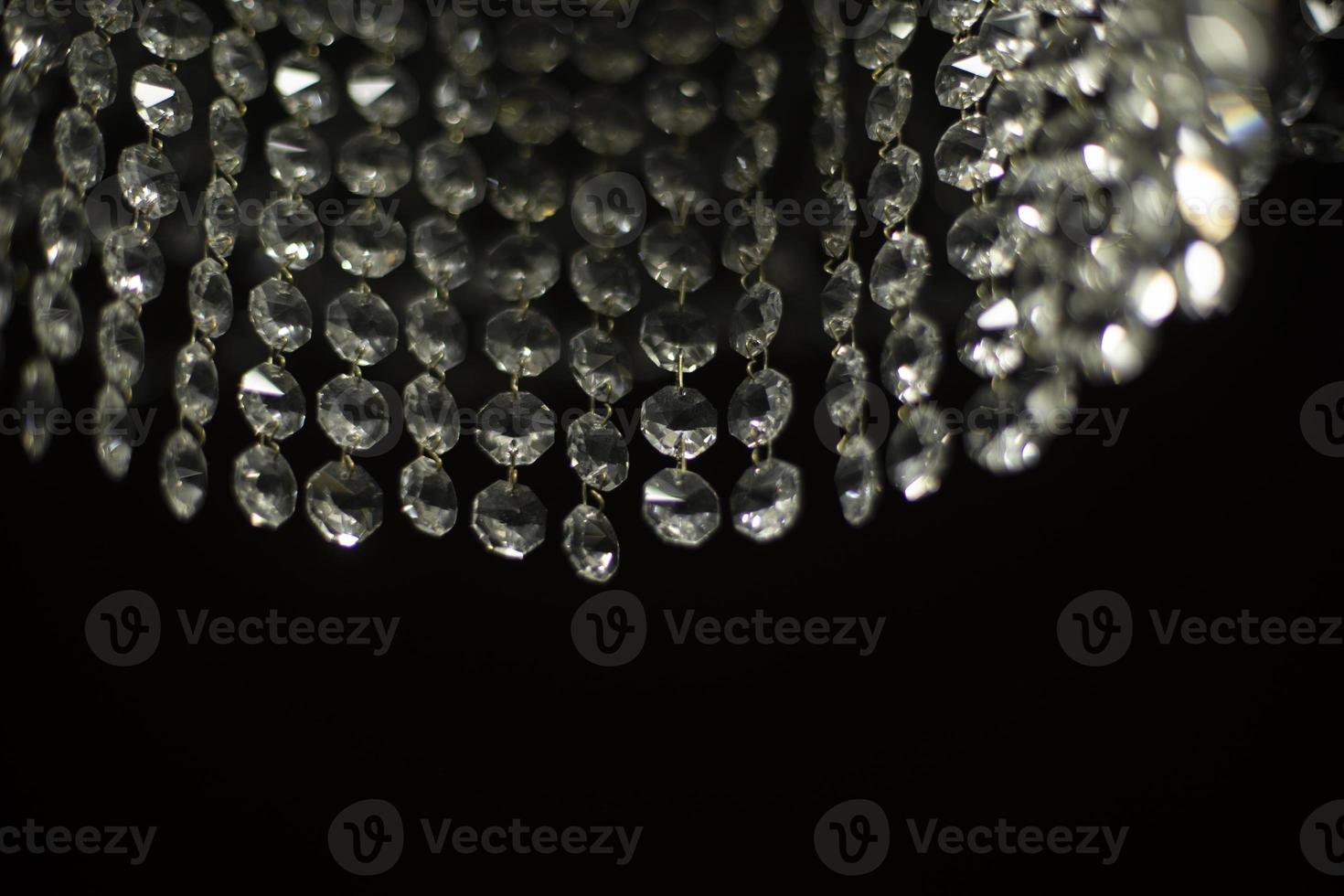 Crystal chandelier on black background. Interior details. Light in room. Light source. Glass sticks. photo