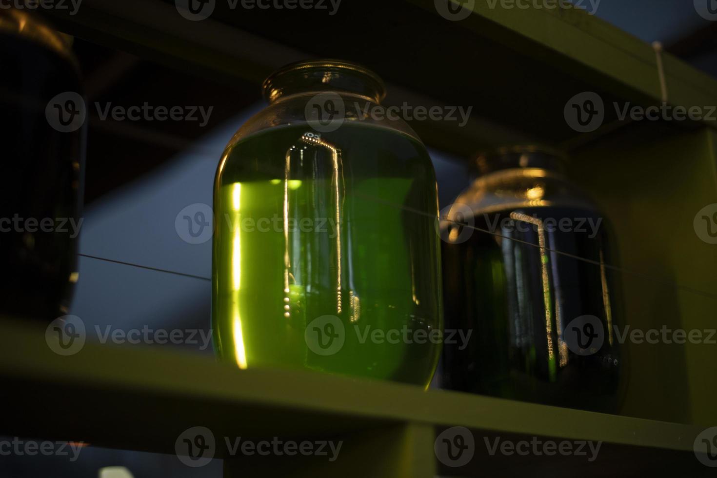 Jar with green liquid. Transparent capacity. Bar interior. photo