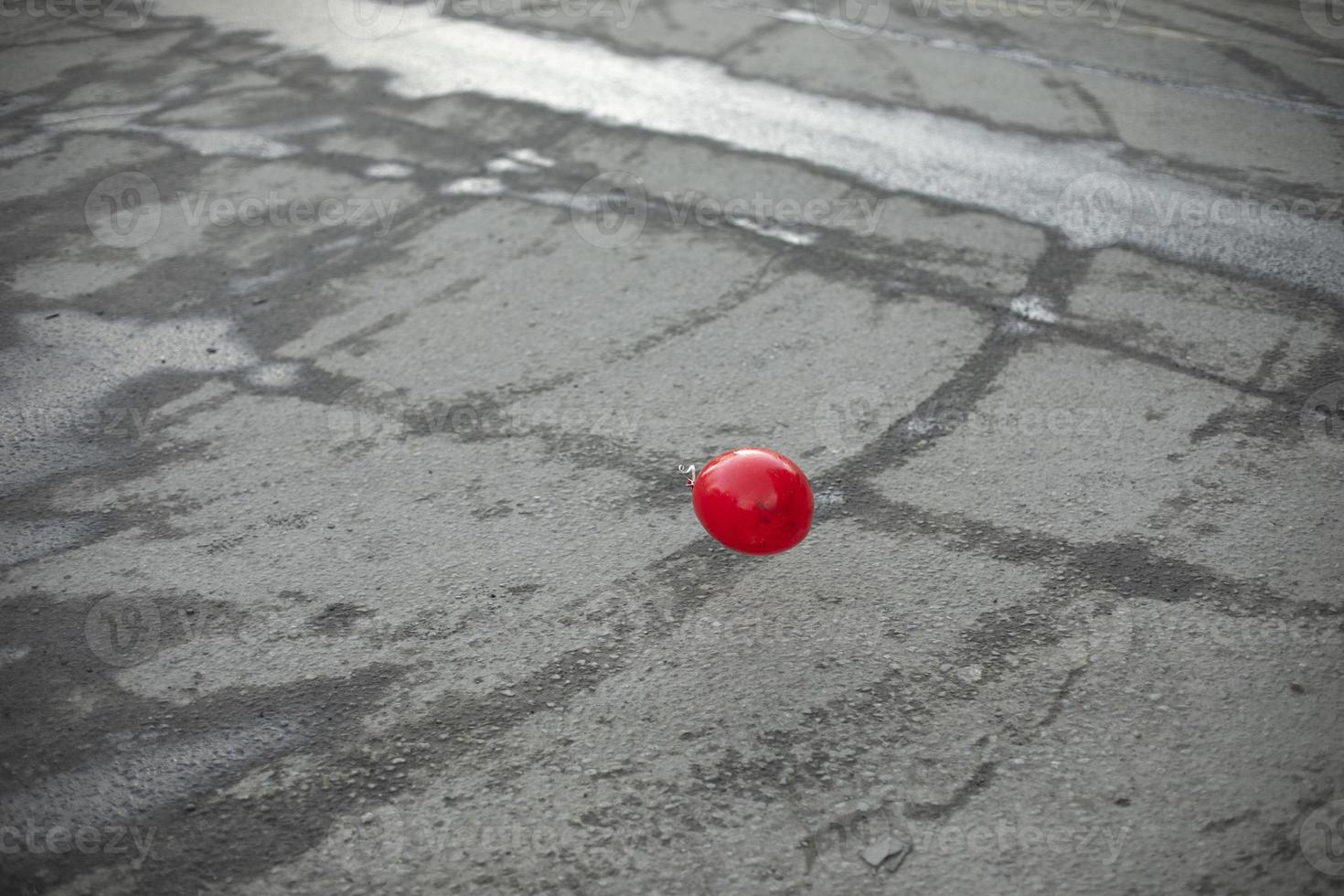 Red ball on background of asphalt. Abstract art. Sphere made of plastic. photo