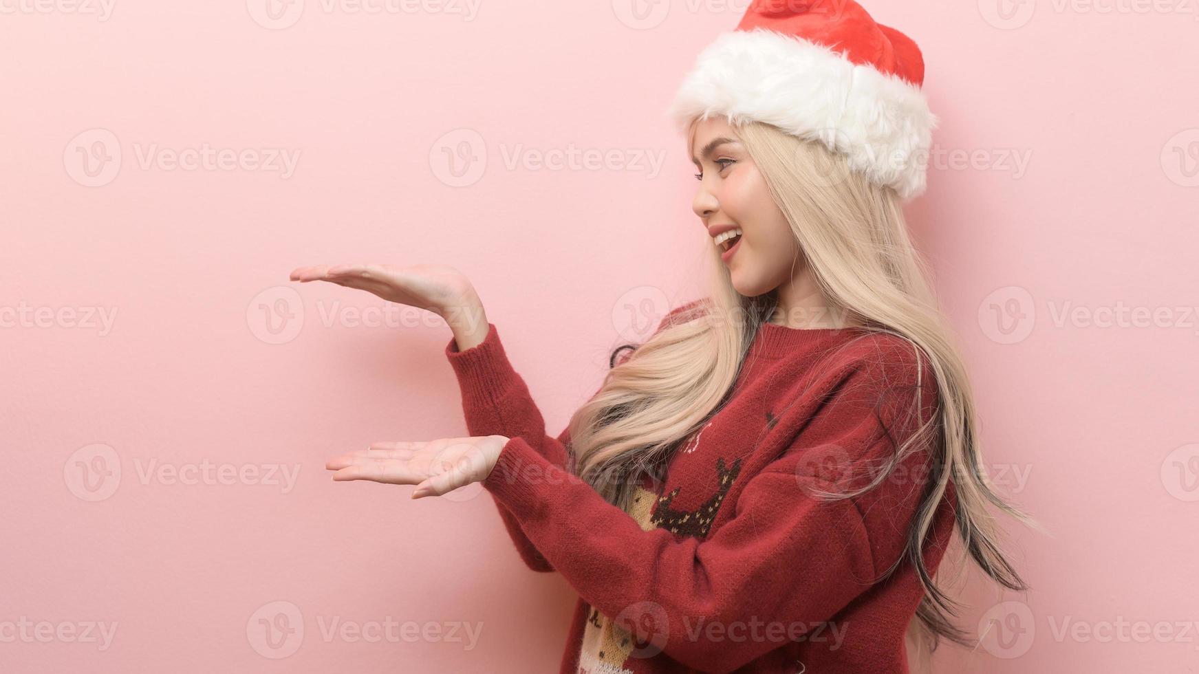 Portrait of happy Caucasian young woman in santa claus hat over pink background photo