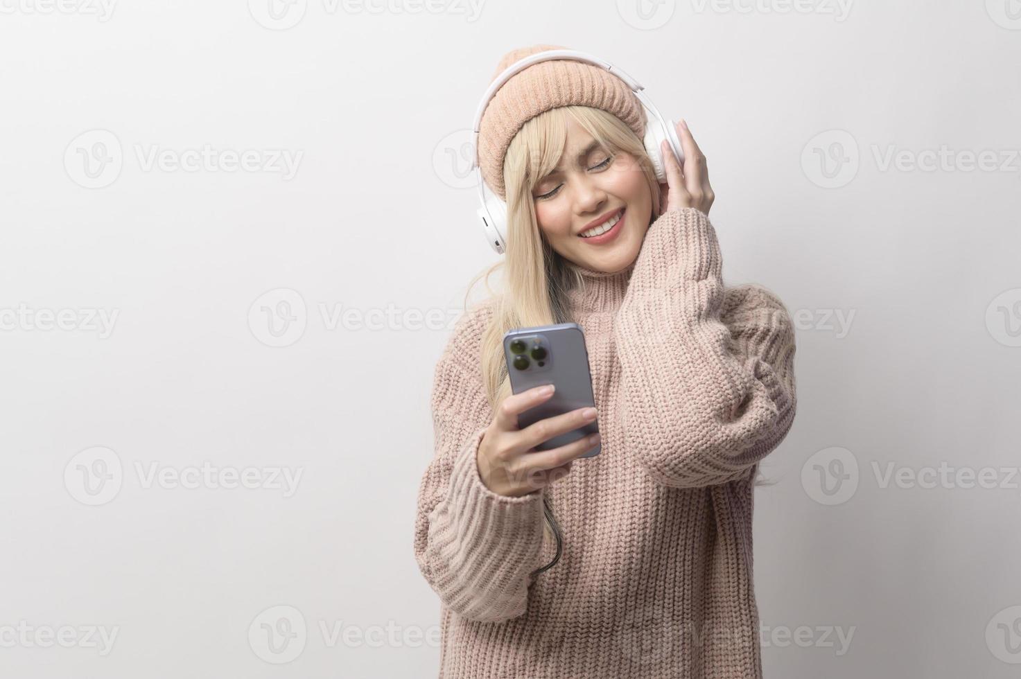 retrato de una joven caucásica con suéter sosteniendo un teléfono inteligente sobre fondo blanco foto