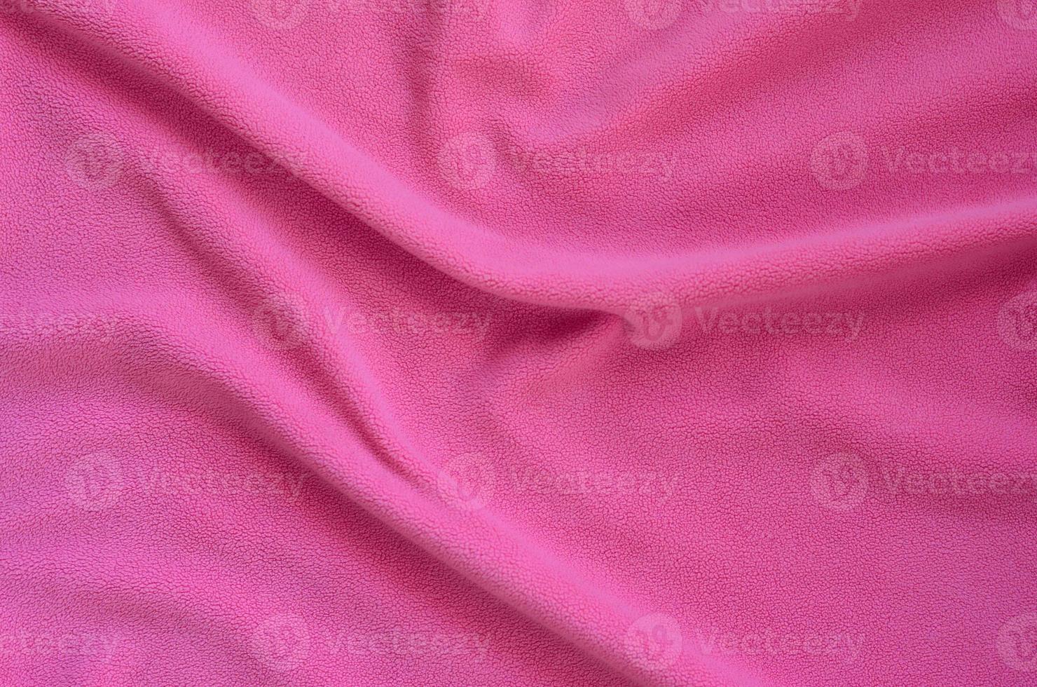 The blanket of furry pink fleece fabric. A background of light pink soft plush fleece material with a lot of relief folds photo