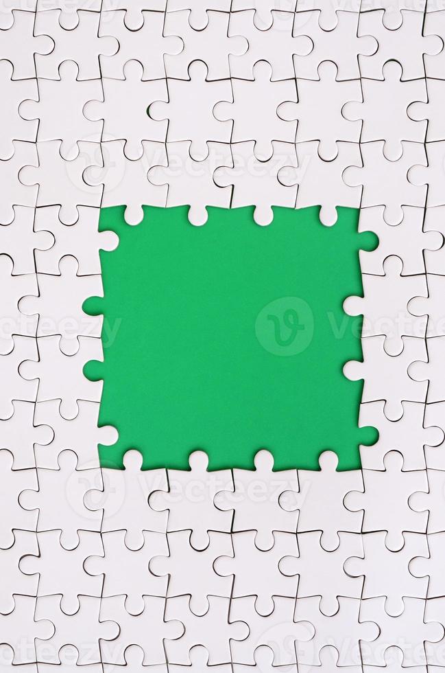 Framing in the form of a rectangle, made of a white jigsaw puzzle around the green space photo