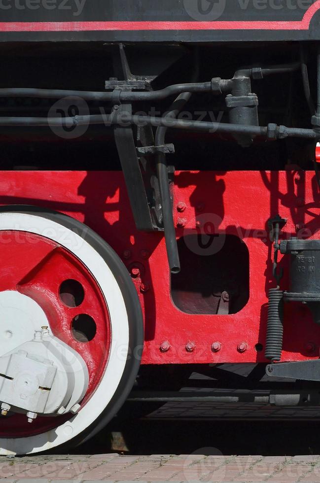 Wheels of the old black steam locomotive of Soviet times. The side of the locomotive with elements of the rotating technology of old trains photo