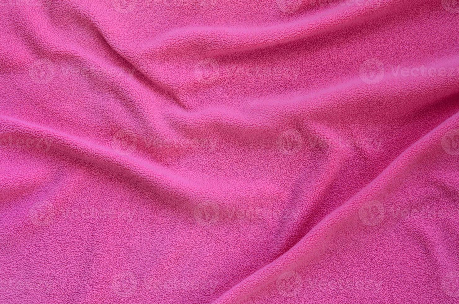 The blanket of furry pink fleece fabric. A background of light pink soft plush fleece material with a lot of relief folds photo