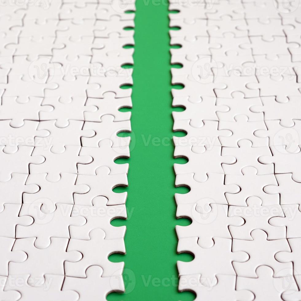 The green path is laid on the platform of a white folded jigsaw puzzle. Texture image with copy space for text photo