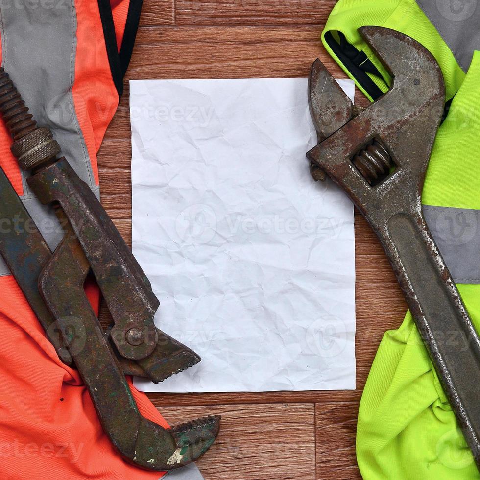 Adjustable wrenches and paper lies of an orange and green signal worker shirts photo