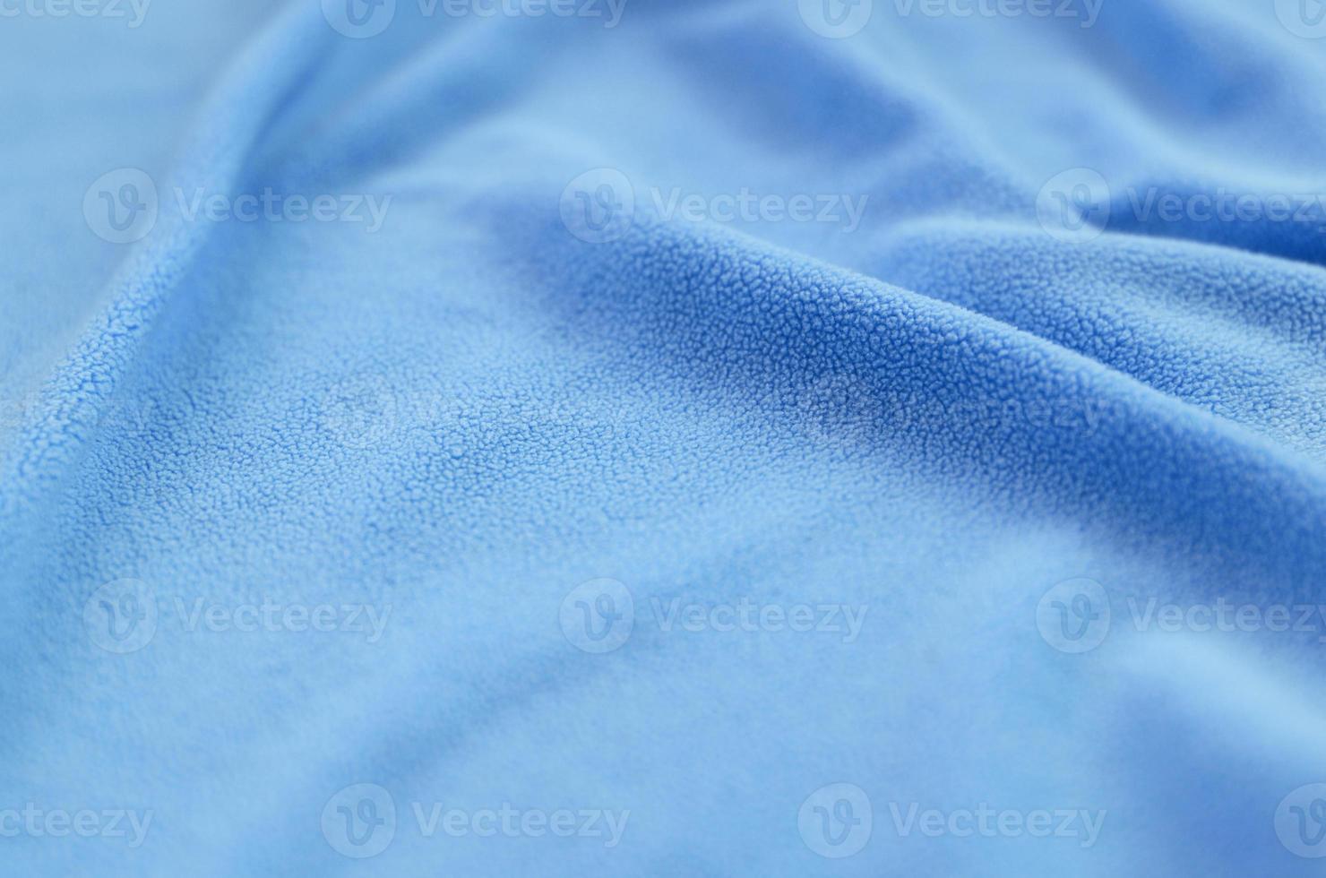 The blanket of furry blue fleece fabric. A background of light blue soft plush fleece material with a lot of relief folds photo
