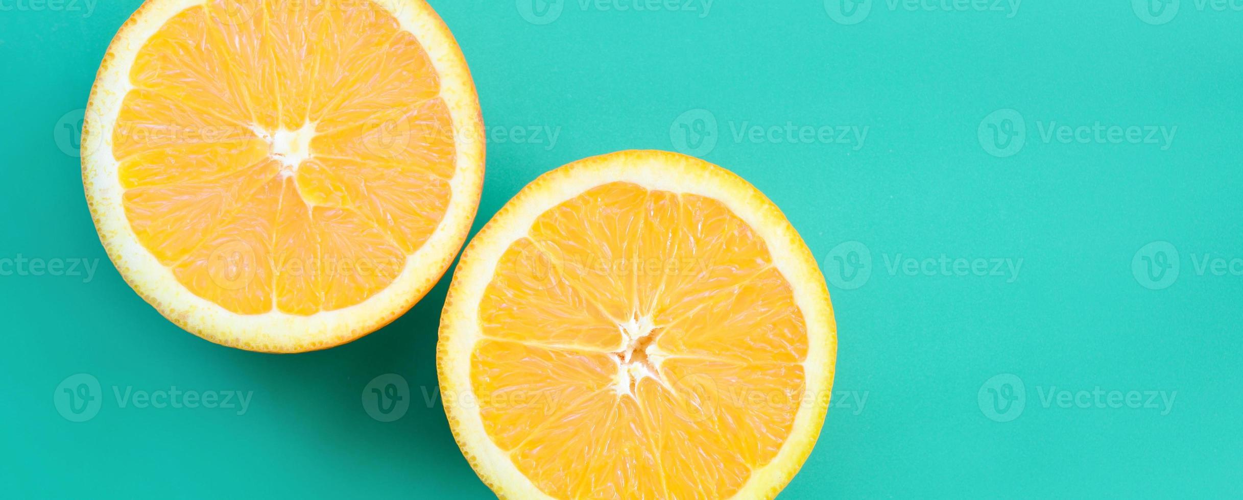 Top view of a several orange fruit slices on bright background in turquoise green color. A saturated citrus texture image photo