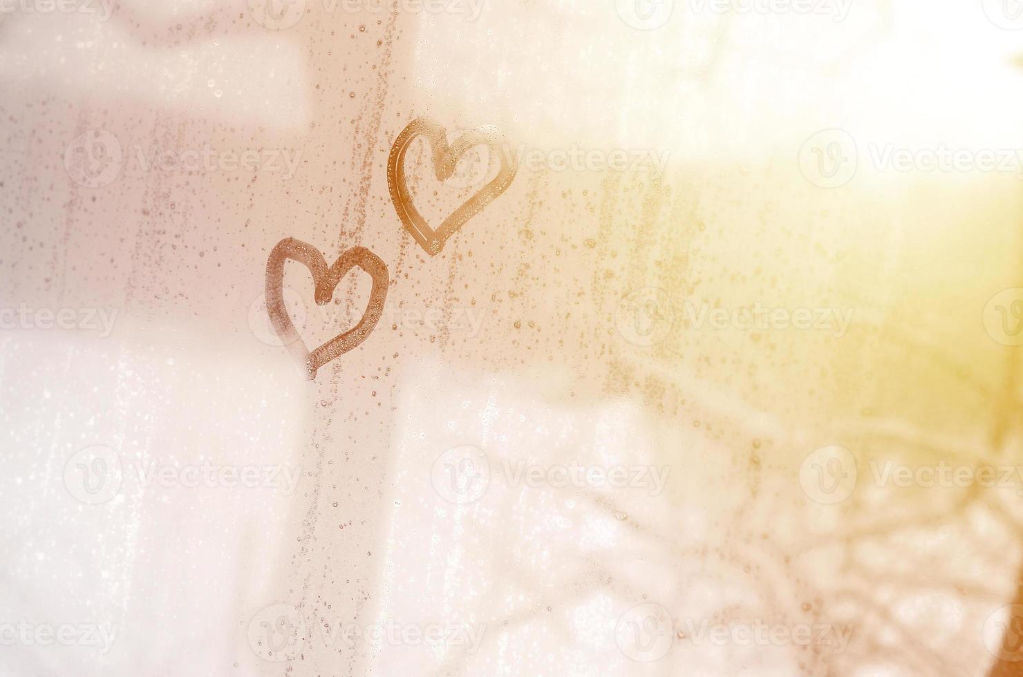 Two hearts painted on a misted glass in winter photo