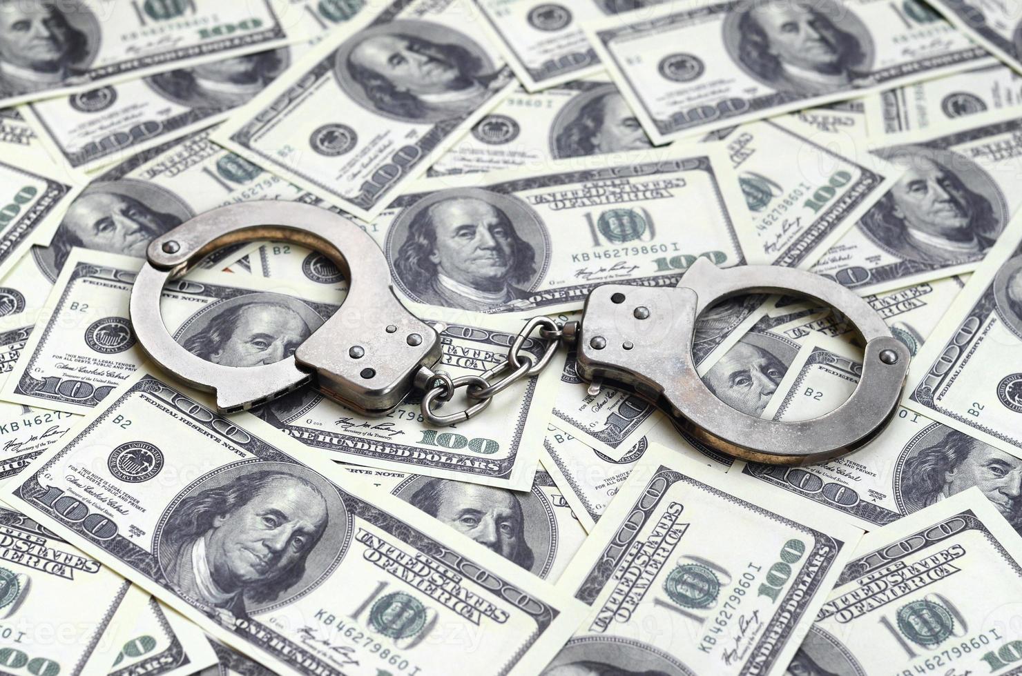 Police handcuffs lie on a lot of dollar bills. The concept of illegal possession of money, illegal transactions with US dollars. Economic Crime photo