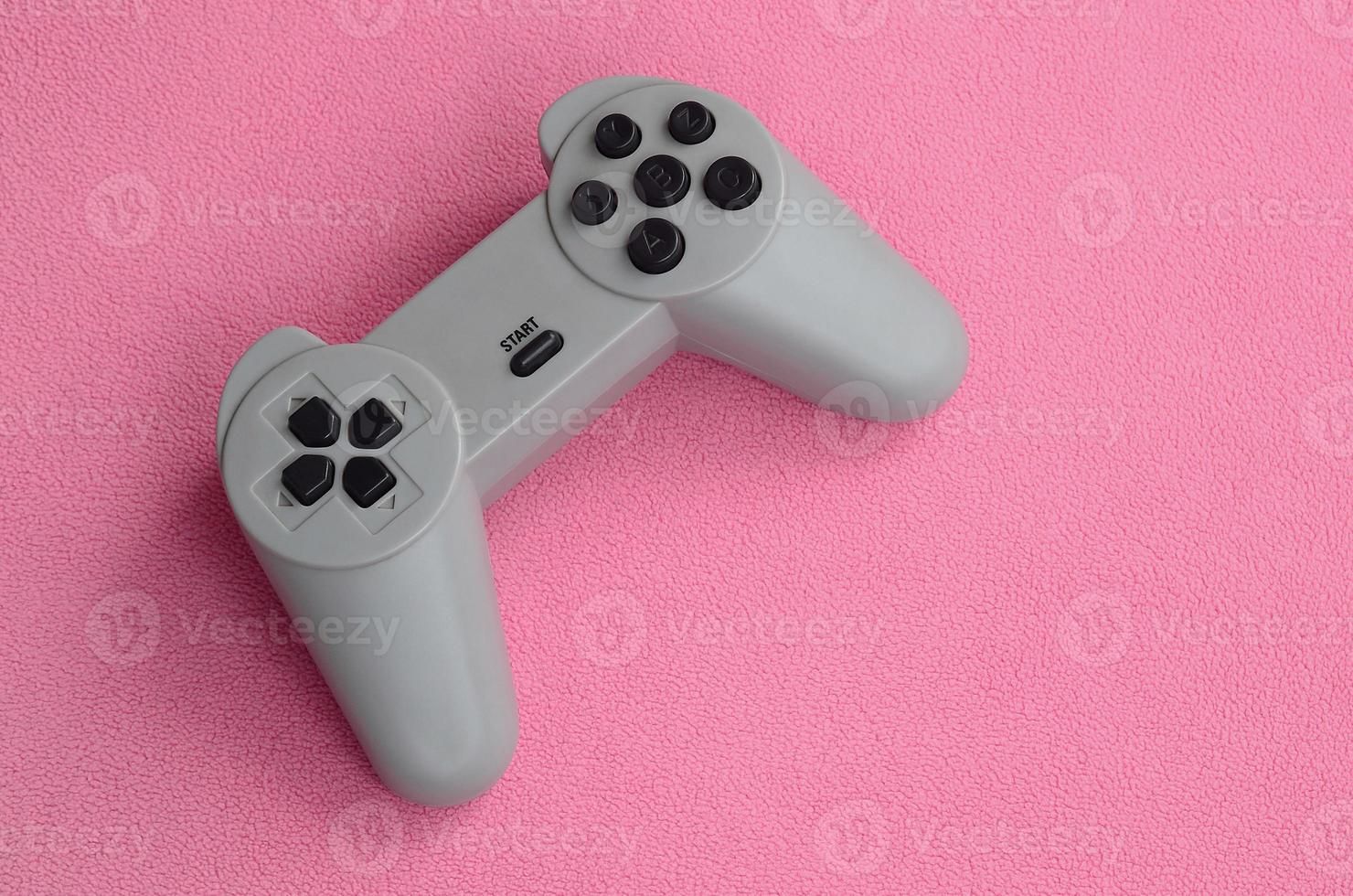 Playing games concept. Single pad joystick lies on the blanket of furry pink fleece fabric. Controller for video games on a background texture of light pink soft plush fleece material photo