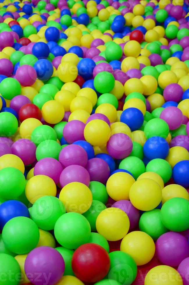 Many colorful plastic balls in a kids' ballpit at a playground. Close up pattern photo