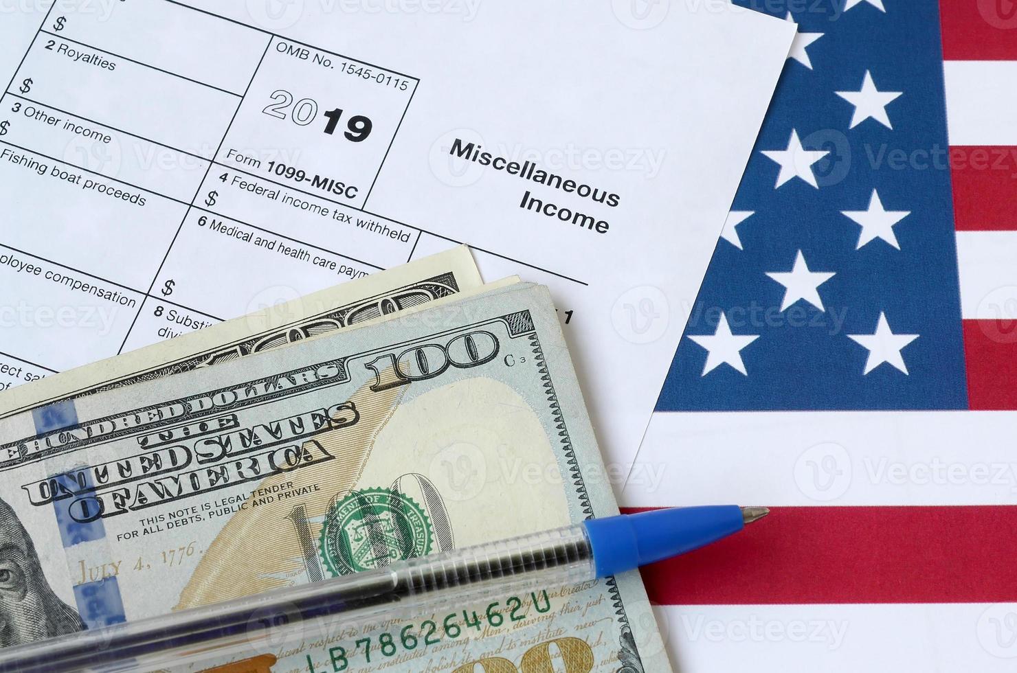 Form 1099-misc Miscellaneous income and blue pen with dollar bills lies on United States flag. Internal revenue service tax form photo