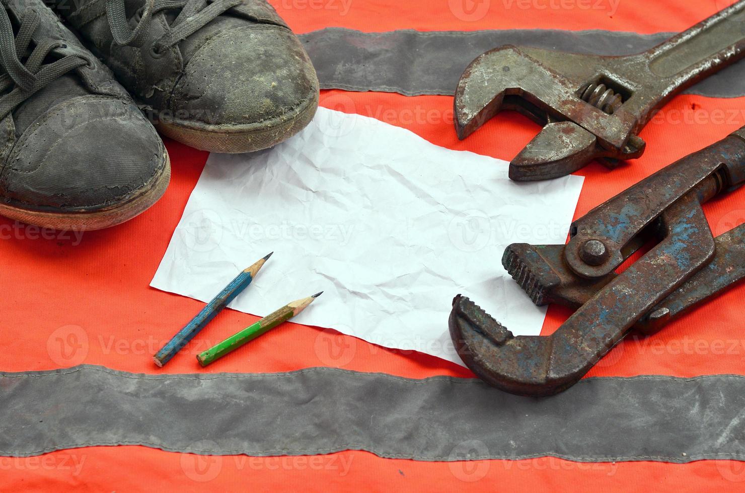 Adjustable wrenches with old boots and a sheet of paper with two pencils photo