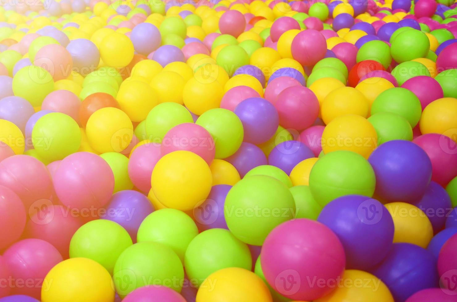 Many colorful plastic balls in a kids' ballpit at a playground. Close up pattern photo