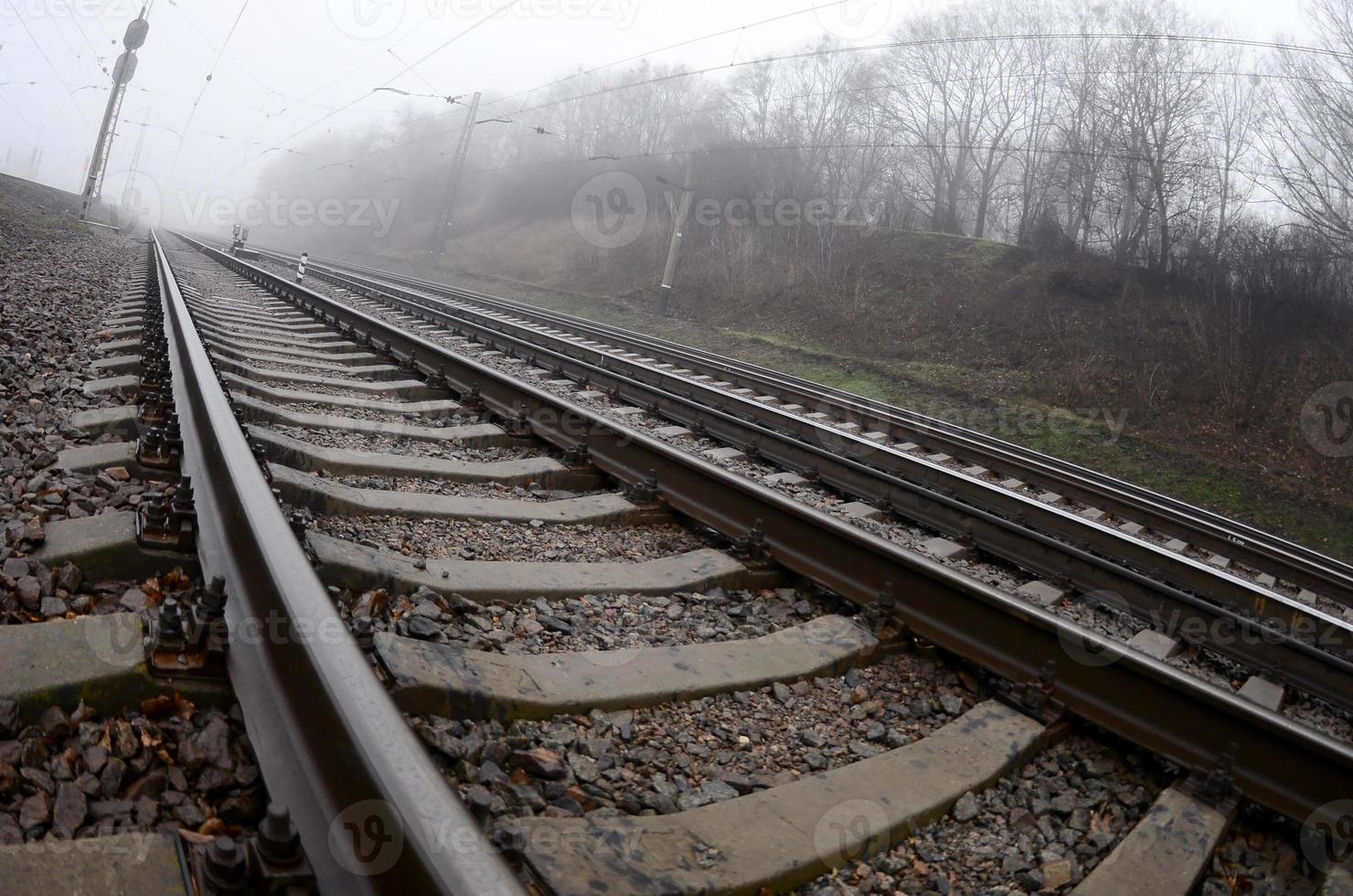 The railway track in a misty morning. A lot of rails and sleepers go into the misty horizon. Fisheye photo with increased distortion