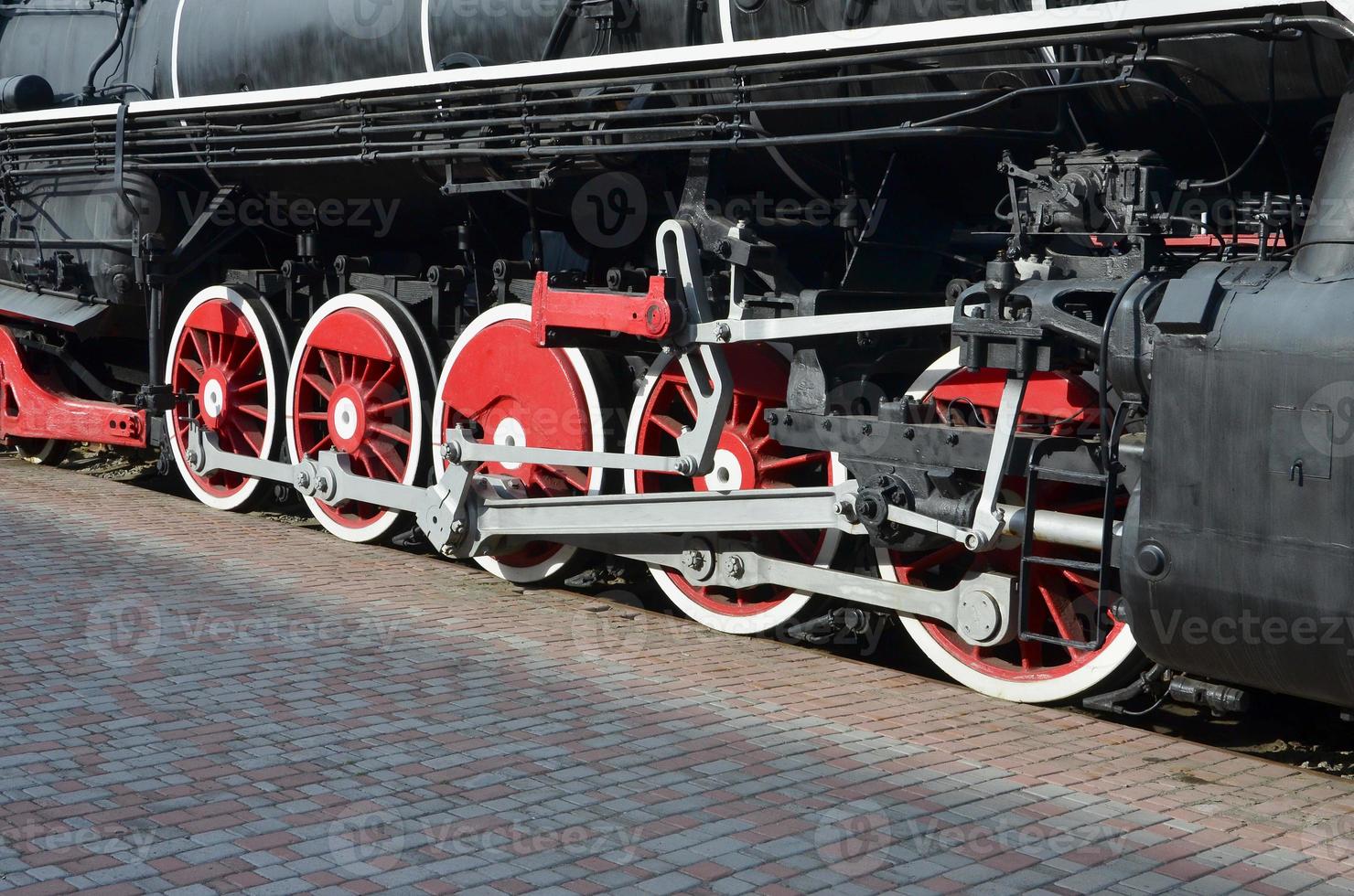 Wheels of the old black steam locomotive of Soviet times. The side of the locomotive with elements of the rotating technology of old trains photo