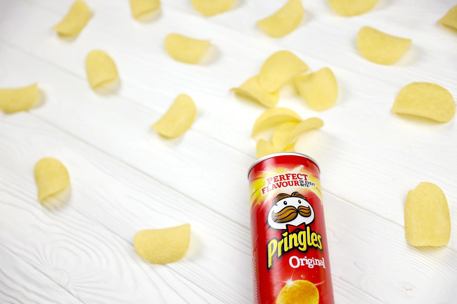 KHARKOV. UKRAINE - MAY 2, 2019 Pringles original flavour. Cardboard tube can with Pringles potato chips on white table. Pringles is a brand of potato snack chips owned by the Kellogg Company photo