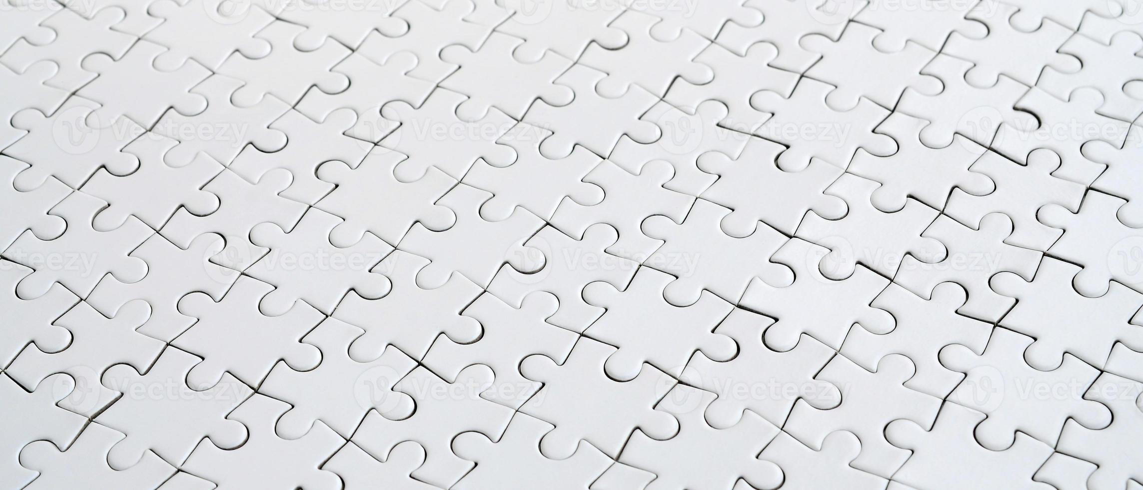 Close up of a white jigsaw puzzle in assembled state in perspective. Many components of a large whole mosaic are united photo