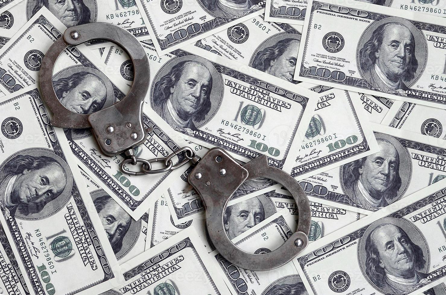 Police handcuffs lie on a lot of dollar bills. The concept of illegal possession of money, illegal transactions with US dollars. Economic Crime photo