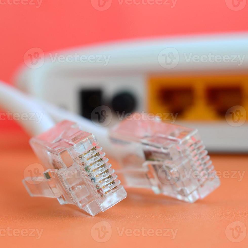 el enrutador de Internet y los enchufes del cable de Internet se encuentran sobre un fondo naranja brillante. elementos necesarios para la conexión a internet foto