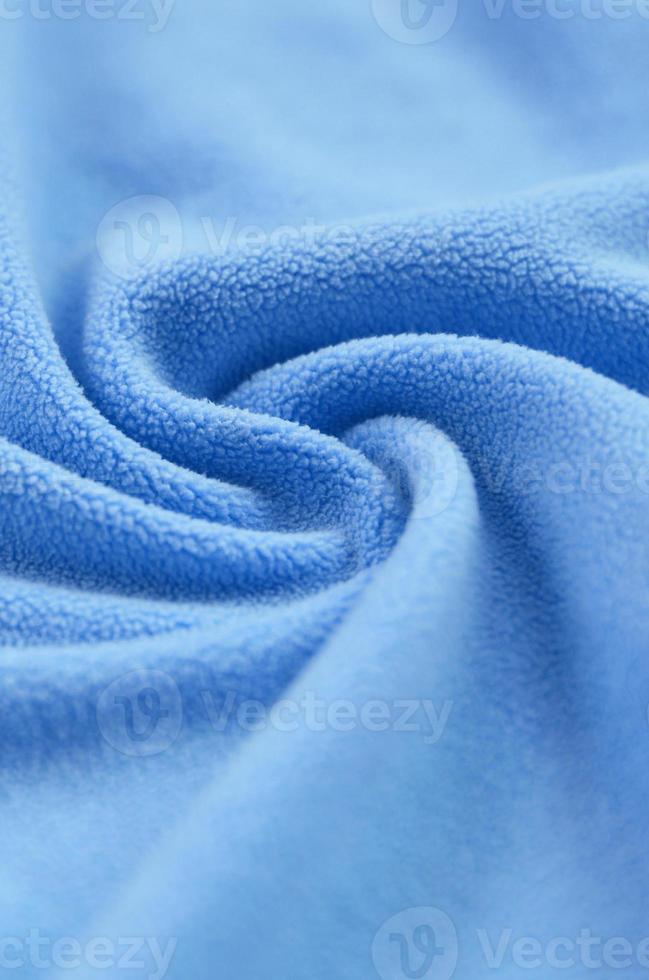 The blanket of furry blue fleece fabric. A background of light blue soft plush fleece material with a lot of relief folds photo
