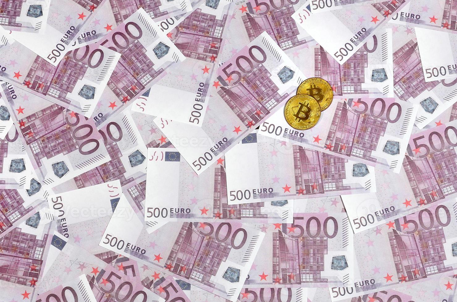 Bitcoins over pile of five hundred euro banknotes. Traditional money versus cryptocurrency concept. Gold coin above 500 euro bills. Close up photo