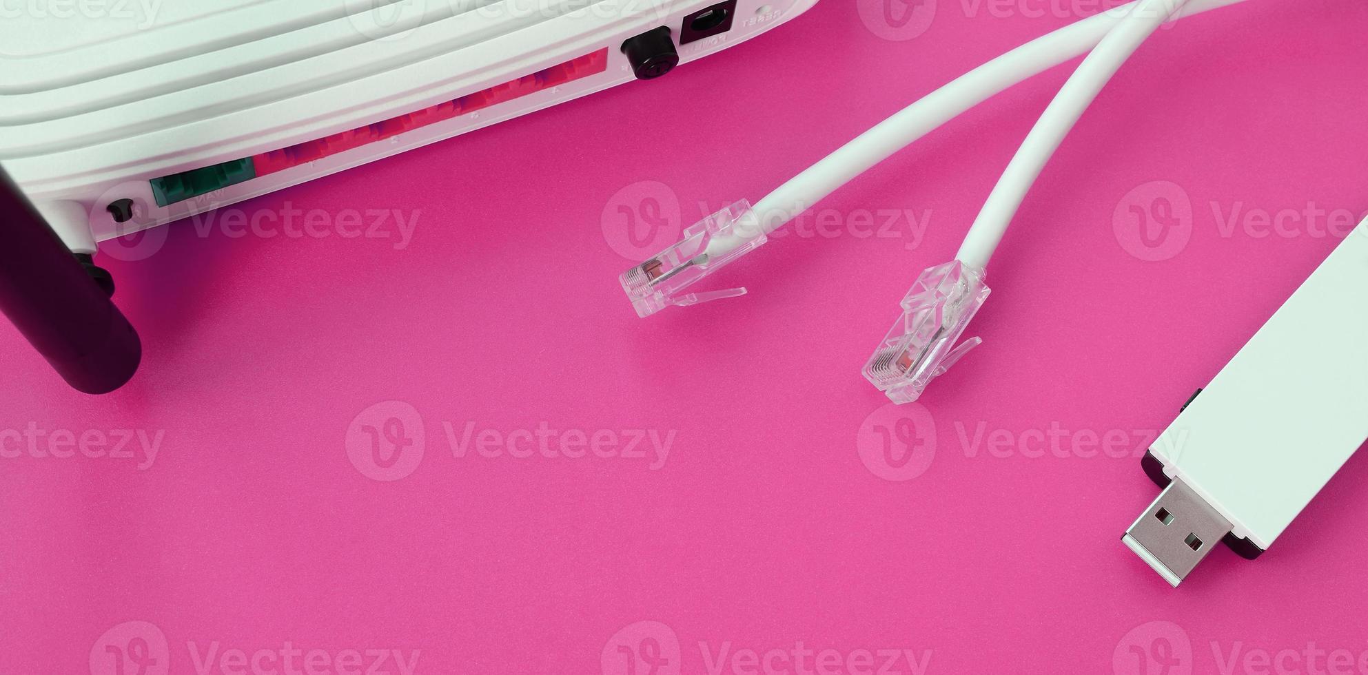 Internet router, portable USB wi-fi adapter and internet cable plugs lie on a bright pink background. Items required for internet photo