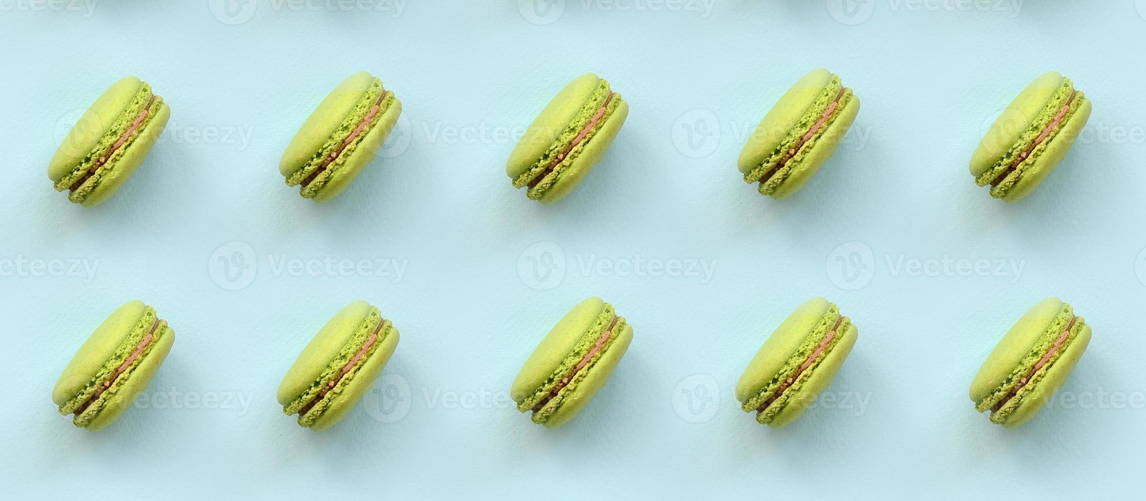 Green dessert cake macaron or macaroon on trendy pastel blue background top view. Flat lay pattern composition photo