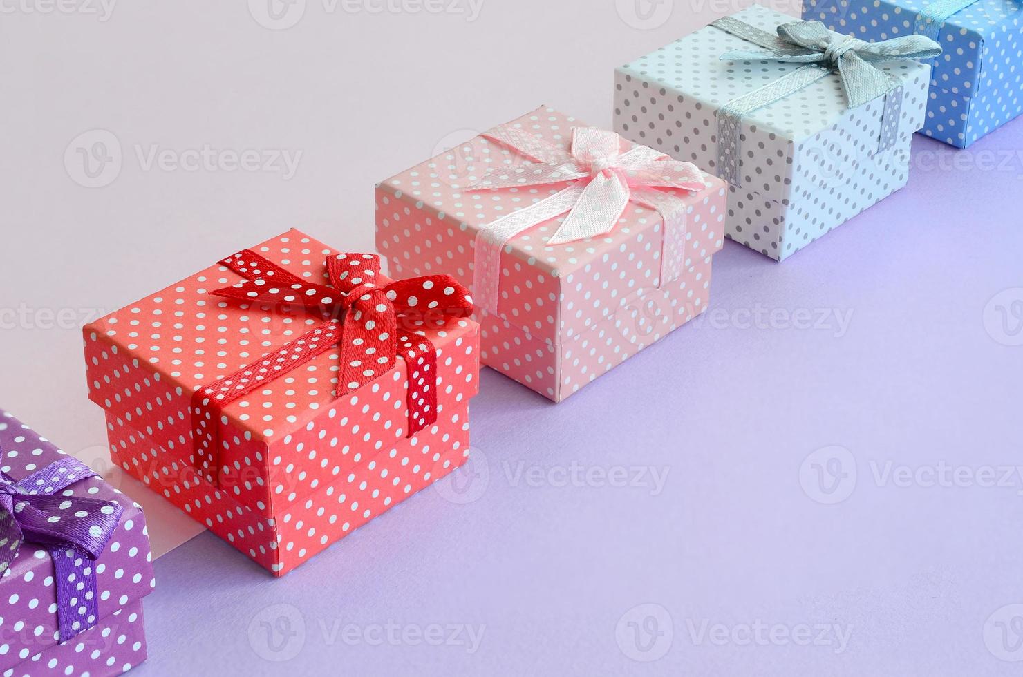 Small gift boxes of different colors with ribbons lies on a violet and