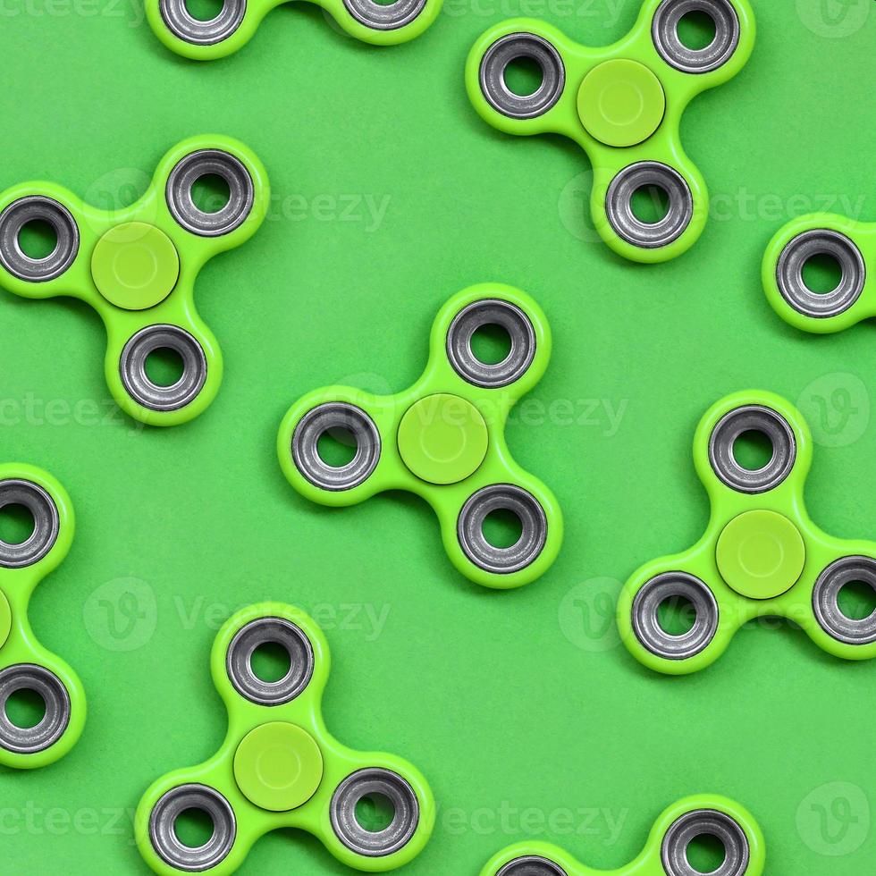 Many green fidget spinners lies on texture background of fashion pastel green color paper in minimal concept photo