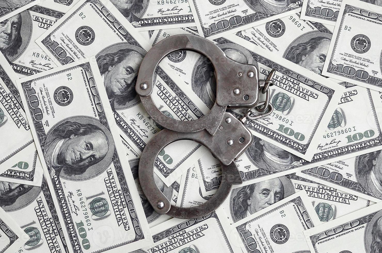 Police handcuffs lie on a lot of dollar bills. The concept of illegal possession of money, illegal transactions with US dollars. Economic Crime photo