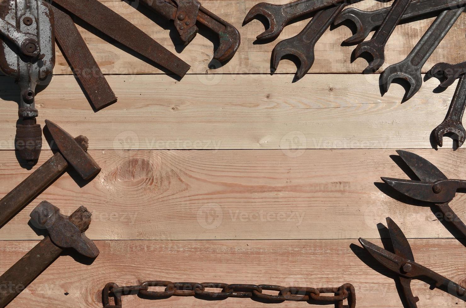 A set of old and rusty tools lies on a wooden table in the workshop photo