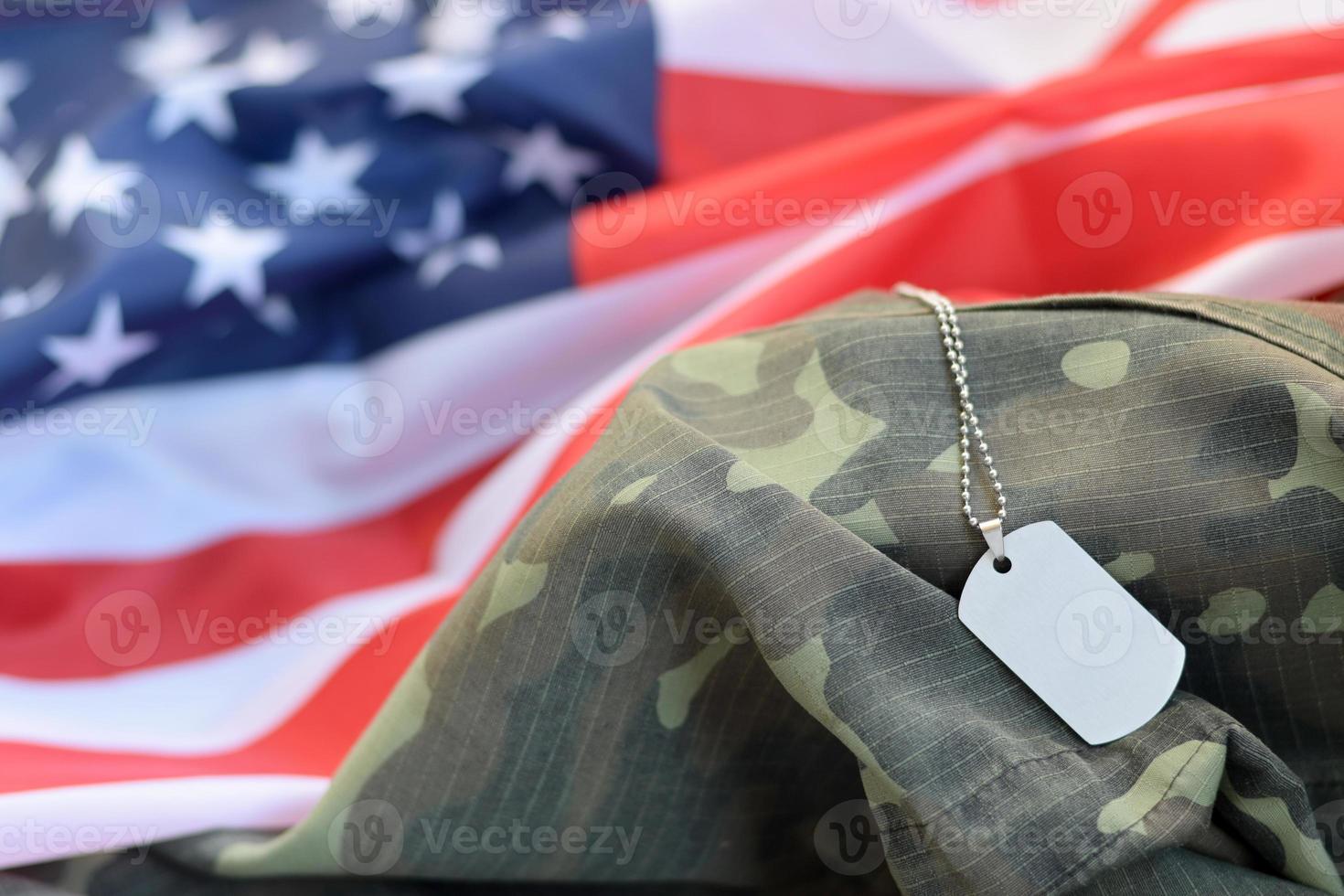 Silvery military beads with dog tag on United States fabric flag and camouflage uniform photo