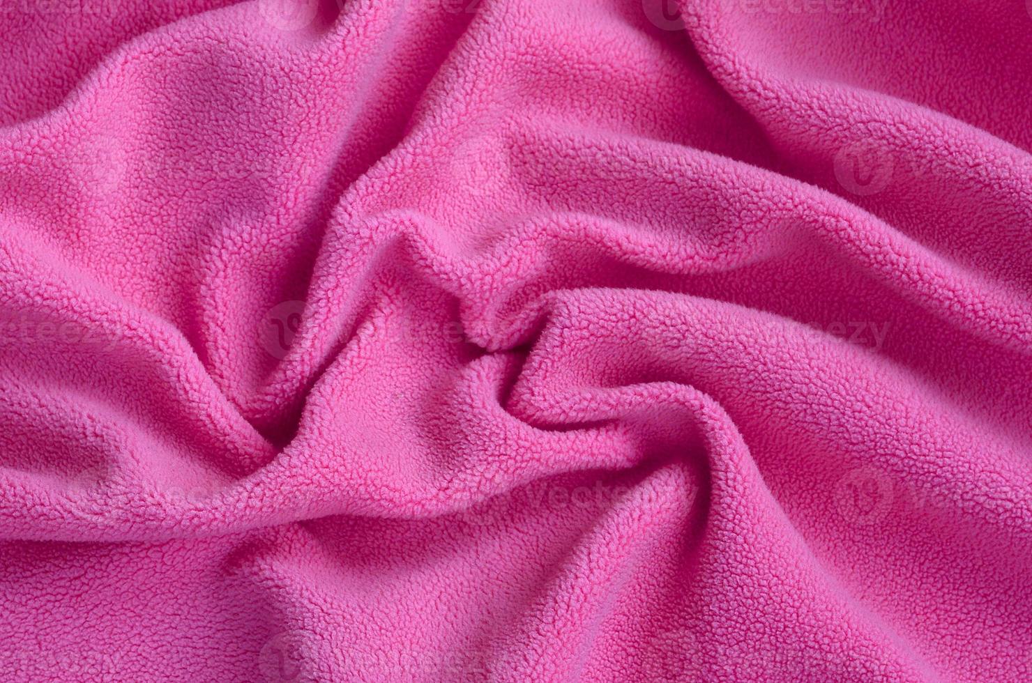 The blanket of furry pink fleece fabric. A background of light pink soft plush fleece material with a lot of relief folds photo