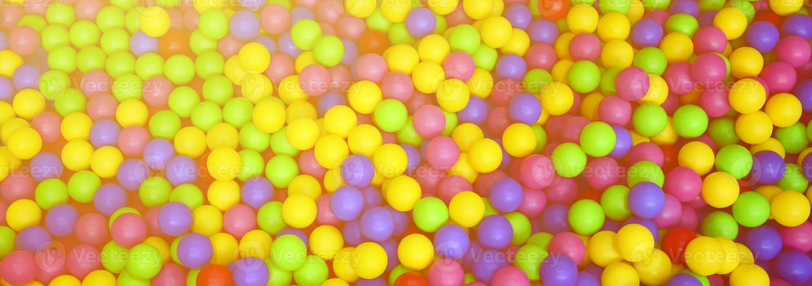 Many colorful plastic balls in a kids' ballpit at a playground. Close up pattern photo